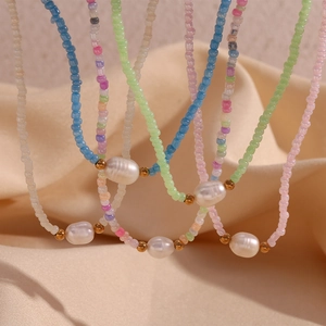 Colorful beaded necklaces with freshwater pearls and gold beads on a beige fabric background