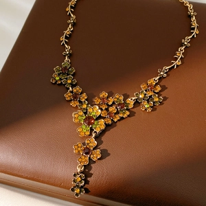 Vue détaillée du collier vintage en bronze avec strass floraux verts et orange sur fond cuir