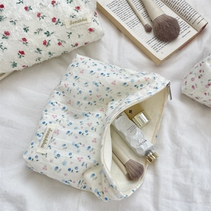 Detailed close-up of floral lace makeup bags with blue and red patterns and Sorakka label