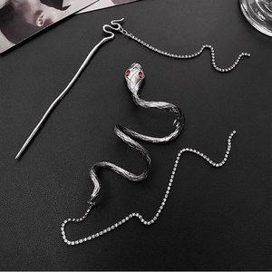 Silver snake hair pin with tassel and red gemstone eyes on black leather background