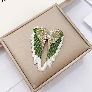 Macro shot of angel wing brooch with green gradient enamel and sparkling rhinestones