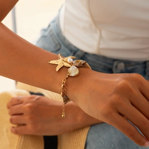 Detail of a gold starfish necklace with pearls and shell pieces on a female model