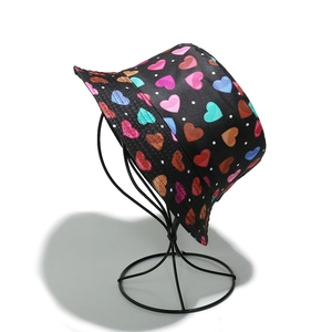 Cappello da pescatore nero con cuori colorati e pois bianchi su un supporto