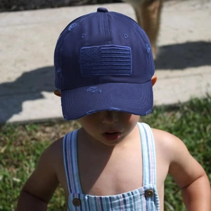 Détail d'une casquette baseball enfant bleue au style usé avec broderie du drapeau USA