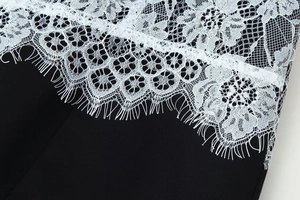 Gros plan sur la bordure en dentelle florale blanche raffinée d'une robe noire