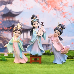 Three Chinese ancient beauty figurines in traditional Hanfu on green grass
