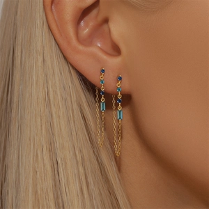 Detail of S925 silver tassel star earrings with blue zircon stones on golden chains