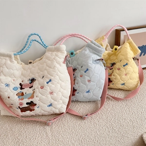 Detailed embroidery of cartoon dachshunds on quilted heart pattern tote bags in soft colors