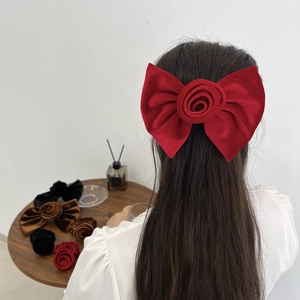 Détail d'une grande pince à cheveux rose en velours rouge avec variantes noire et marron