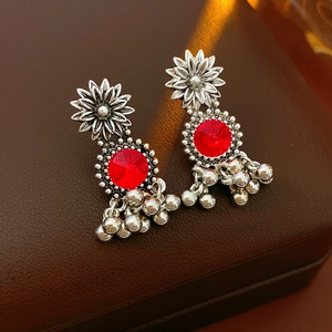 Detail of vintage silver earrings with red gemstones on brown leather surface
