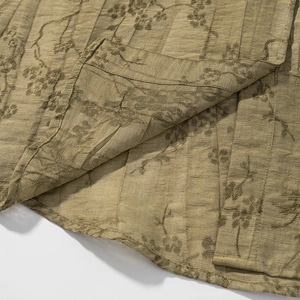 Close-up of olive green jacquard fabric with floral patterns and natural fiber texture