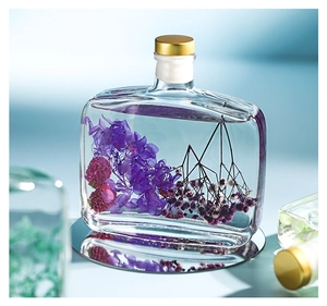 Close-up of glass reed diffuser bottle with purple dried flowers in liquid on mirror