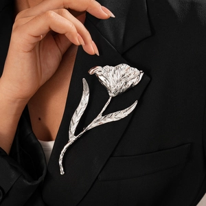 Macro shot of silver metal tulip brooch with detailed texture on a black blazer lapel
