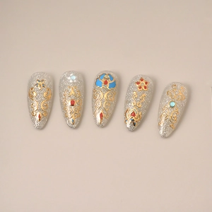 Detail of stiletto press-on nails with silver glitter base and gold palace patterns