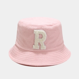 Detail of pink bucket hat featuring fuzzy white letter R patch on textured bouclé fabric