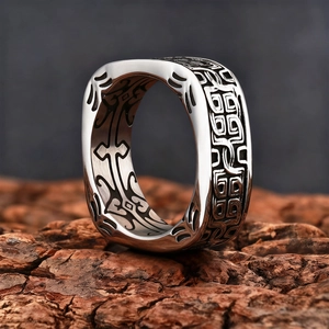 Detailed view of wide square men's ring with ancient beast pattern on wood background