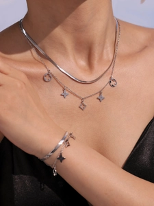 Vue détaillée du collier et bracelet argentés multicouches avec pendentifs trèfle étoilé