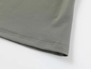 Close-up of double-needle stitching and ribbed fabric hem on a grey crop top