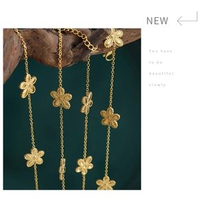 Detailed close-up of gold flower necklace on wood branch against dark green background