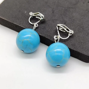 Close-up of blue turquoise clip-on earrings with silver metal and golden textures