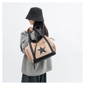 Detailed side view of beige canvas shoulder bag with black star logo and fashion tag