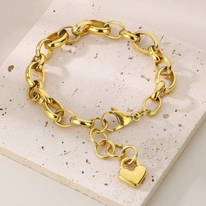 Close-up of 18K gold plated oval chain bracelet with heart pendant on white stone