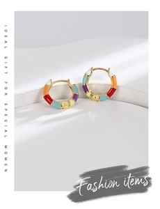 Macro shot of bamboo-shaped gold earrings with colorful enamel on white stone background