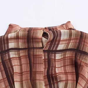 Macro detail of plaid midi dress featuring back collar button and fine pleats