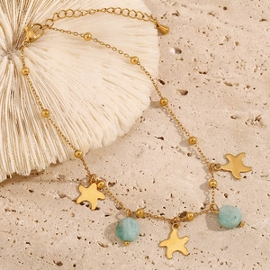 Detailed shot of 18K gold plated starfish anklet with light blue stones on white coral