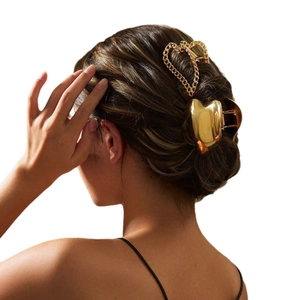 Elegant gold metal heart-shaped claw clip with chain detail shown on styled hair