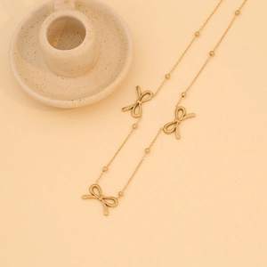 Detailed view of golden stainless steel necklace with delicate bow accents and small beads