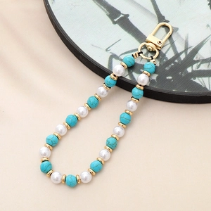 Detail of handmade beaded lanyard with green stones, pearls and golden lobster clasp
