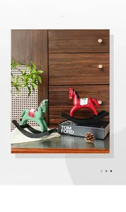 Détail de statues de chevaux à bascule vintage rouges et verts sur un meuble en bois décoratif