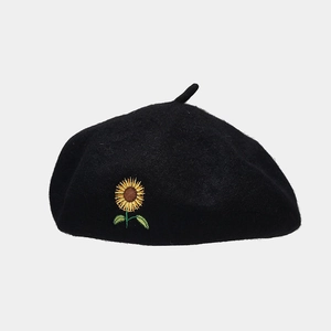 Close-up of vibrant sunflower embroidery on a premium black wool beret hat