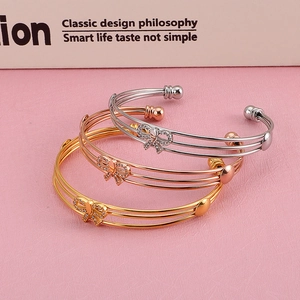 Lot de trois joncs ouverts papillon évidés à strass en finitions or, argent et rose doré