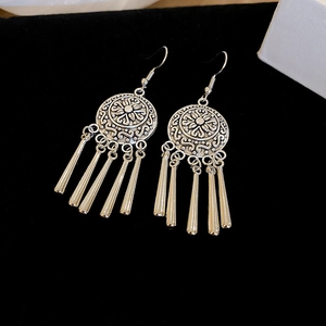 Detailed macro of vintage silver ethnic earrings with hollow floral disc and fringe tassels