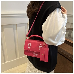 Hot pink shoulder bag with skull print and small coin purse shown on a model