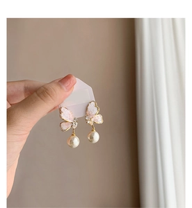 Detail of butterfly earrings with pink stones, pearls, and crystals on gold hooks