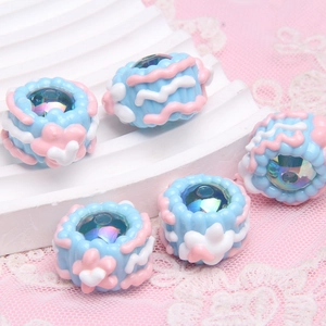 Macro detail of hand-painted blue resin beads with pink waves for DIY jewelry making