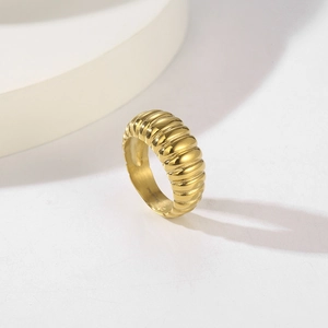 Detailed view of gold stainless steel ring with ribbed croissant texture on white decor