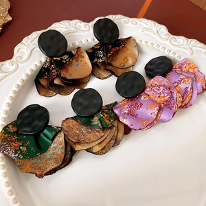 Three pairs of irregular petal earrings with textured black metal studs on white tray