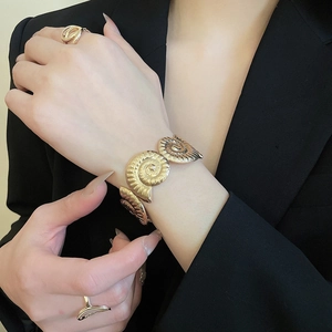 Detailed view of gold wrinkled starfish cuff bracelet and matching spiral rings on a model