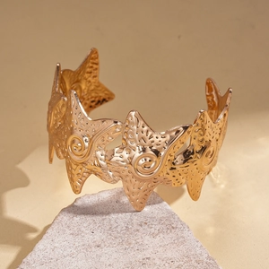 Macro shot of gold starfish cuff bracelet featuring detailed oceanic textures and metal finish