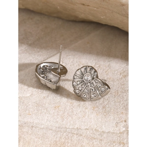 Macro shot of silver shell-shaped earrings with rhinestones on a natural rock background