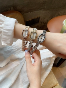 Nahaufnahme einer eleganten achteckigen Damenuhr mit Strass-Lünette und Metallarmband