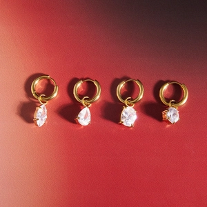 Detailed close-up of gold hoop earrings set with marquise and teardrop zircon pendants