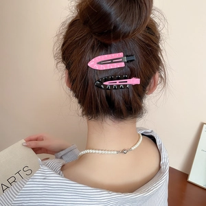 Detail of pink and black triangle duckbill hair clips styled on a woman's hair