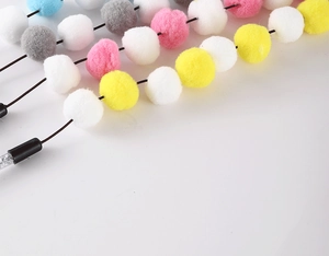 Close-up of colorful plush pom-pom string cat toy with vibrant yellow and blue balls