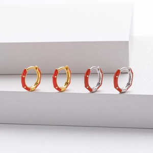 Detail of red enamel hoop earrings with gold and silver finishes on geometric blocks