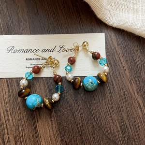 Detail of 18k gold-plated hoop earrings featuring tiger eye, turquoise and crystal beads